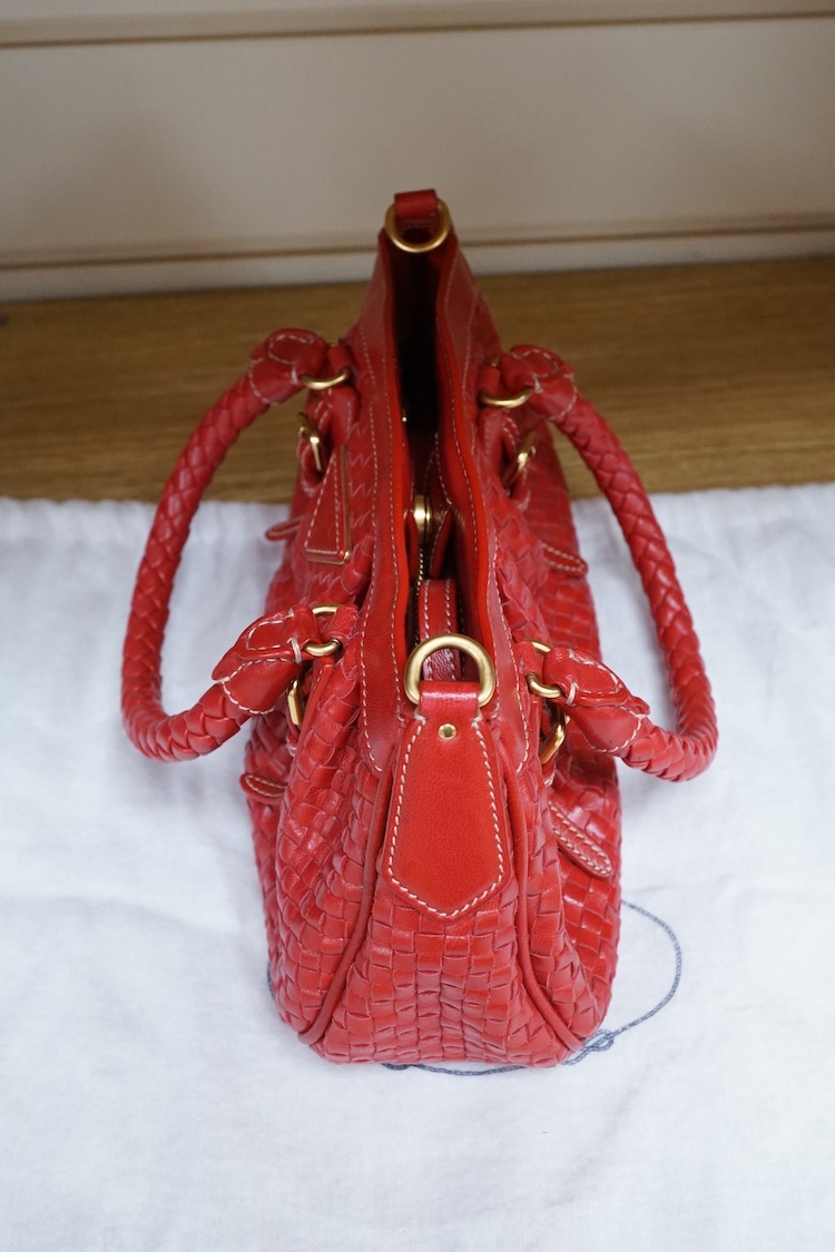A Prada red braided leather handbag with shoulder strap, authenticity card and dust cover, 25cm wide, Provenance: Purchased by the vendor in Selfridges